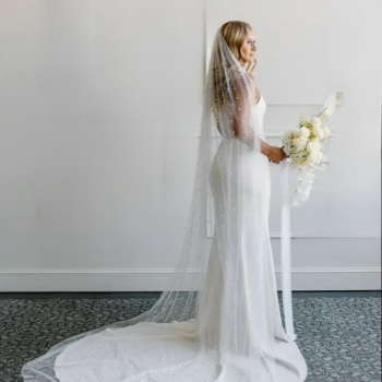 Bride wearing long pearl veil scattered with lots of pearls showing side view